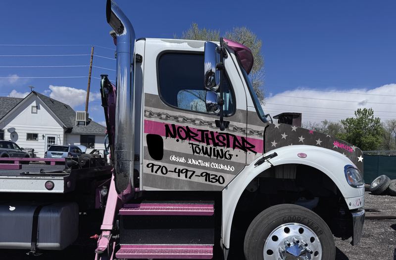 Design mockup of the NorthStar Towing wrap on a tow truck cab: pink, gray and white stripes with chain and star details