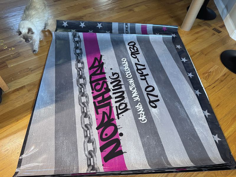 Printed NorthStar Towing wrap panel laid out on a wood floor with a cat walking past