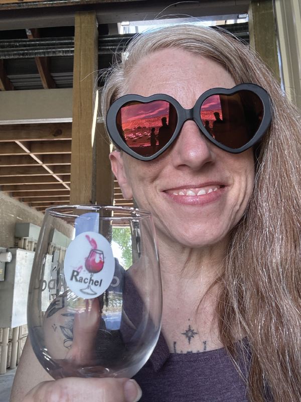 Smiling person in heart-shaped sunglasses holding a wine glass with a custom name decal